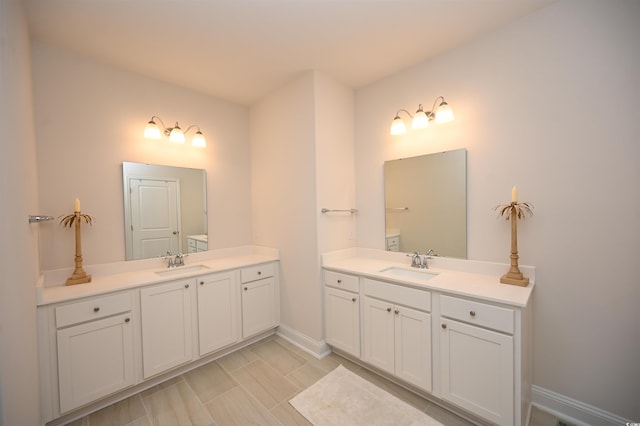 bathroom featuring baseboards, two vanities, and a sink