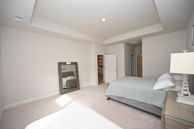 bedroom featuring light colored carpet, a tray ceiling, visible vents, and baseboards