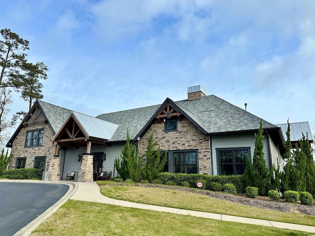 view of front of property featuring a chimney, a front lawn, and stone siding