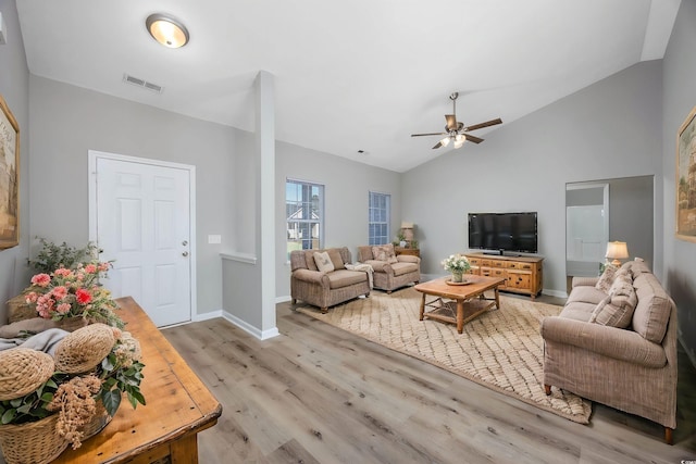 living room with light wood finished floors, a ceiling fan, visible vents, baseboards, and vaulted ceiling