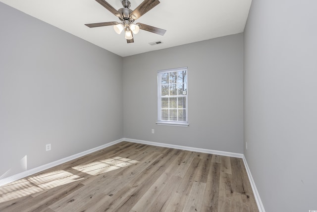 unfurnished room with light wood finished floors, baseboards, a ceiling fan, and visible vents