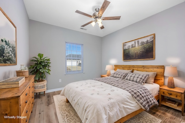 bedroom with baseboards, visible vents, a ceiling fan, and wood finished floors