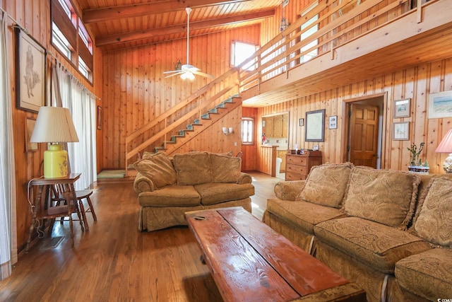living area with ceiling fan, wood ceiling, beam ceiling, wood finished floors, and wood walls
