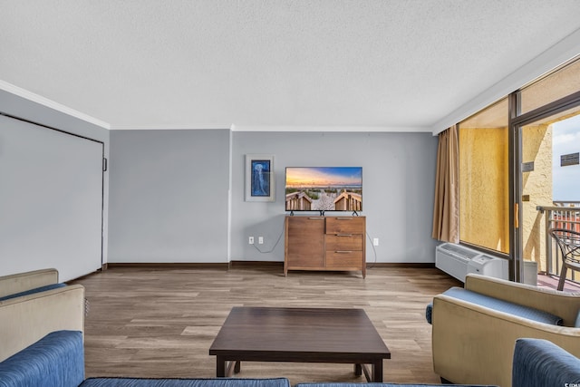 home theater with a textured ceiling, ornamental molding, wood finished floors, an AC wall unit, and healthy amount of natural light