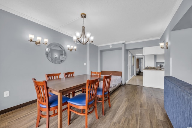 dining room with wood finished floors, a chandelier, ornamental molding, and baseboards