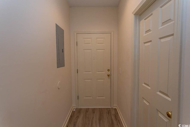doorway with baseboards, wood finished floors, and electric panel