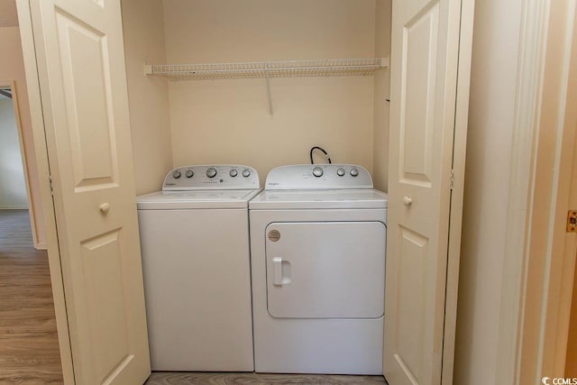 clothes washing area with laundry area, light wood-style flooring, and washing machine and clothes dryer