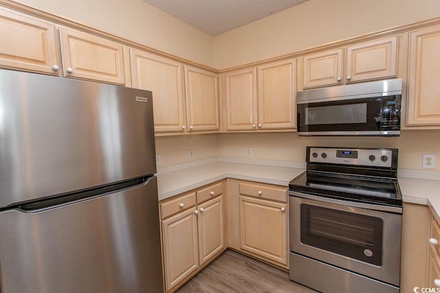 kitchen featuring light brown cabinetry, light wood-style floors, appliances with stainless steel finishes, and light countertops