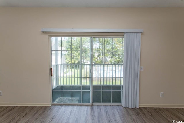 doorway to outside featuring baseboards and wood finished floors