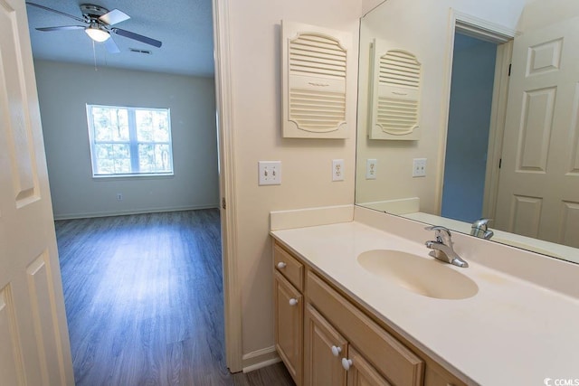 bathroom featuring visible vents, vanity, wood finished floors, baseboards, and ceiling fan
