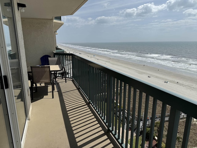 balcony with a water view and a view of the beach