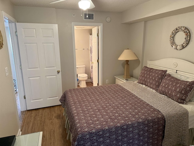 bedroom featuring ensuite bath, visible vents, and wood finished floors