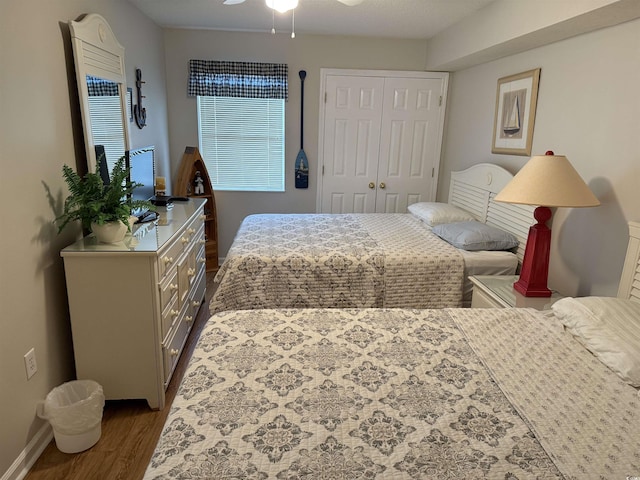 bedroom featuring a closet, baseboards, a ceiling fan, and dark wood-style floors