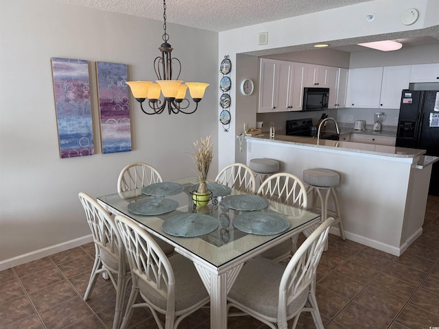 dining area with visible vents, baseboards, dark tile patterned floors, a chandelier, and a textured ceiling