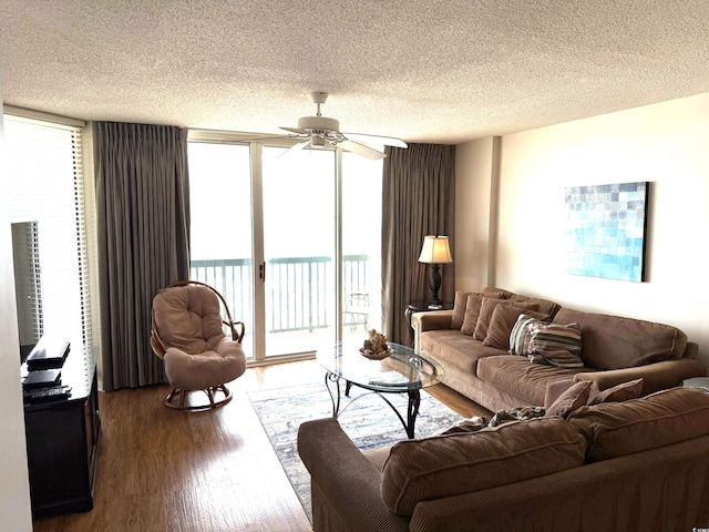 living area with a wealth of natural light, a textured ceiling, a ceiling fan, and wood finished floors