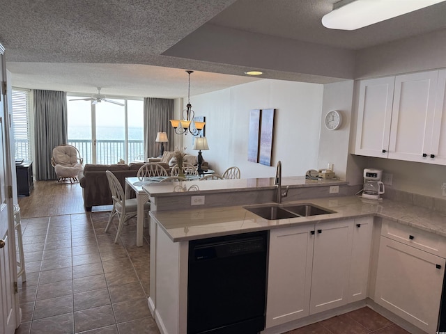 kitchen featuring a peninsula, white cabinetry, dishwasher, a sink, and open floor plan