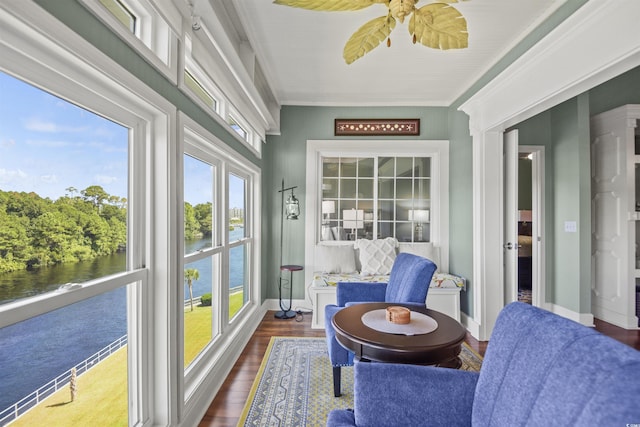 sunroom featuring a water view, wood finished floors, and baseboards