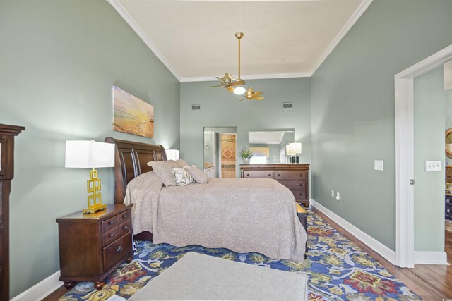 bedroom featuring ornamental molding, baseboards, wood finished floors, a ceiling fan, and connected bathroom