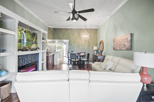 living room with dark wood-style floors, a chandelier, a fireplace, a ceiling fan, and ornamental molding