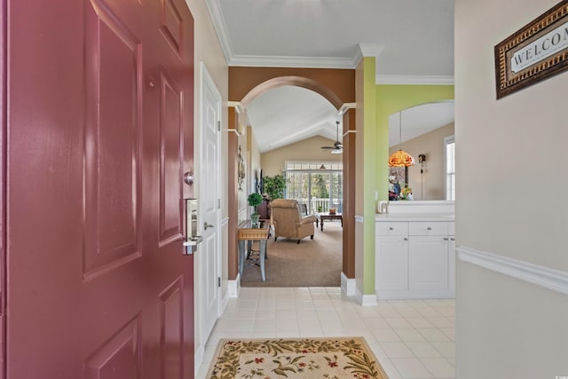 foyer featuring arched walkways, lofted ceiling, light tile patterned flooring, baseboards, and light colored carpet