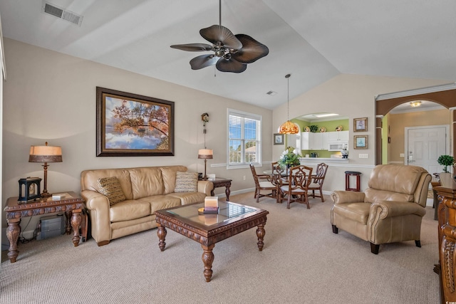living room featuring light colored carpet, vaulted ceiling, ceiling fan, arched walkways, and baseboards