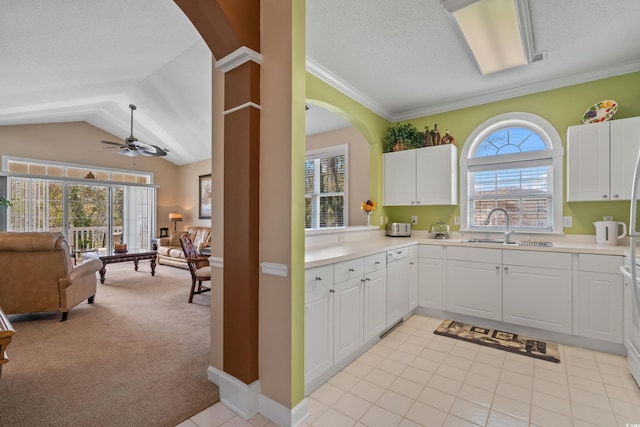 kitchen featuring open floor plan, a sink, dishwasher, white cabinets, and light colored carpet
