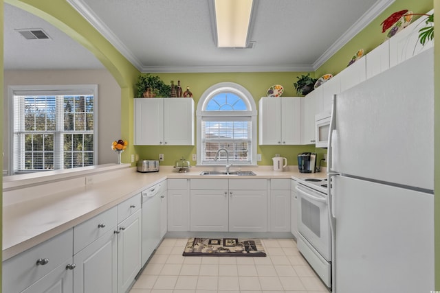 kitchen featuring white appliances, a sink, white cabinets, ornamental molding, and light countertops