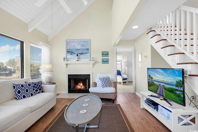living room featuring a fireplace with flush hearth, wood finished floors, high vaulted ceiling, and beam ceiling