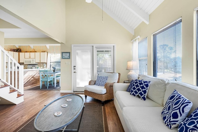 living room featuring a wealth of natural light, stairs, beamed ceiling, and wood finished floors