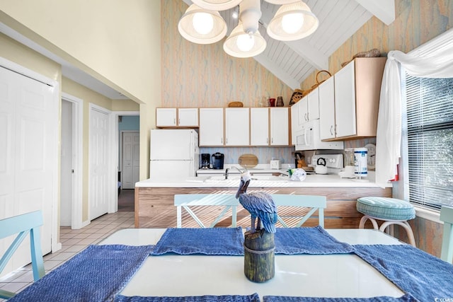 kitchen featuring high vaulted ceiling, freestanding refrigerator, beamed ceiling, light tile patterned floors, and white cabinetry