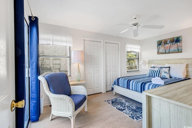 bedroom with ceiling fan, multiple closets, and wood finished floors