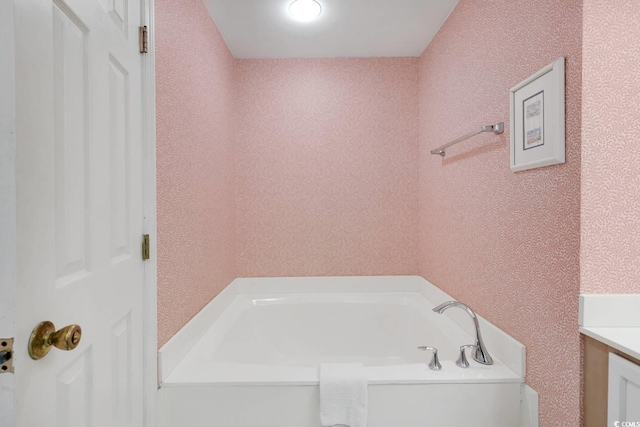 full bath with a garden tub, vanity, and a textured wall