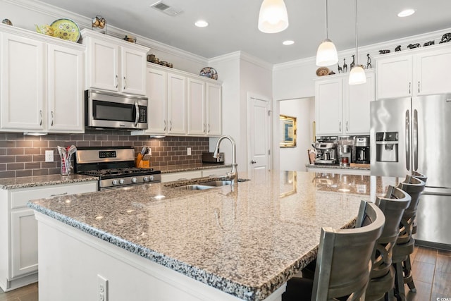 1101 Bronwyn Cir N, Myrtle Beach, SC 29582 - kitchen featuring appliances with stainless steel finishes, a sink, a large island with sink, white cabinetry, and dark wood finished floors