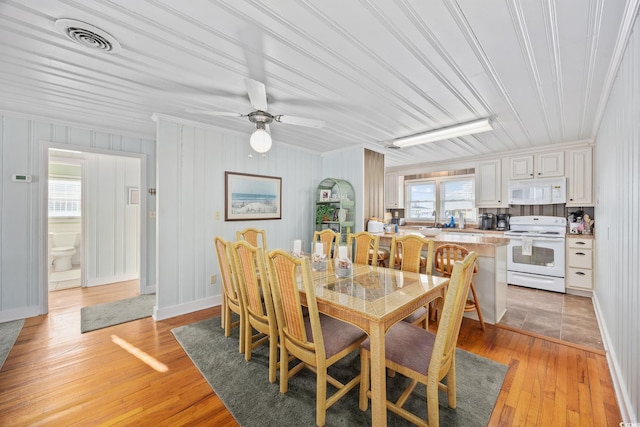 dining area featuring crown molding, light wood-type flooring, visible vents, and ceiling fan