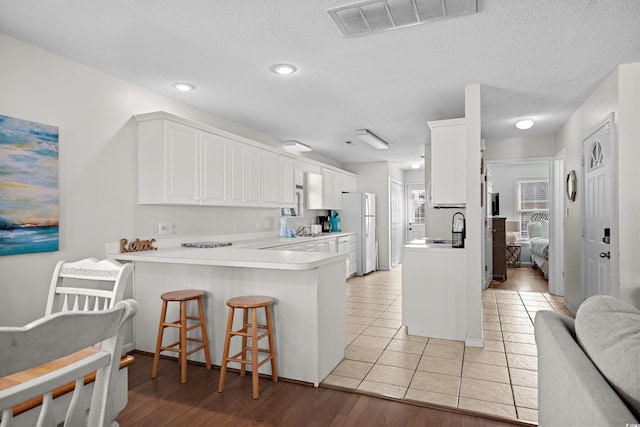 213-A 16th Ave S, Surfside Beach, SC 29575 - kitchen featuring a breakfast bar area, visible vents, a sink, freestanding refrigerator, and a peninsula