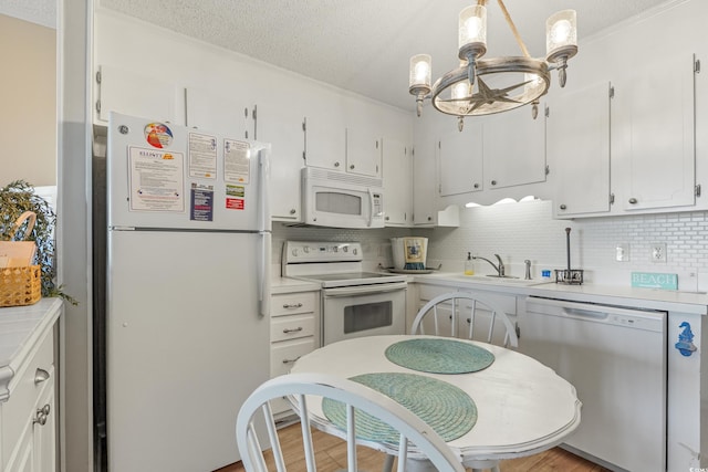 kitchen featuring white cabinets, white appliances, light countertops, and a sink