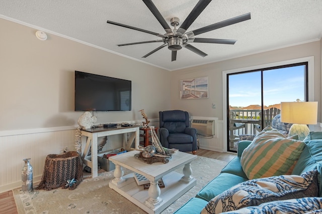 living area with crown molding, a ceiling fan, wainscoting, and wood finished floors