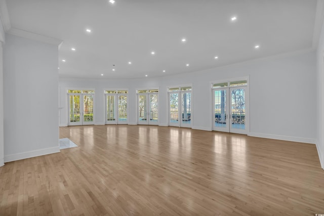 unfurnished living room featuring baseboards, light wood-type flooring, and ornamental molding