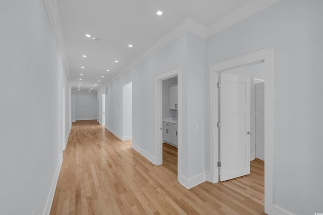 hall with light wood-type flooring, crown molding, baseboards, and recessed lighting
