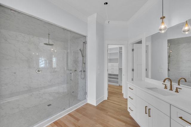 full bathroom featuring a shower stall, vanity, ornamental molding, a spacious closet, and wood finished floors