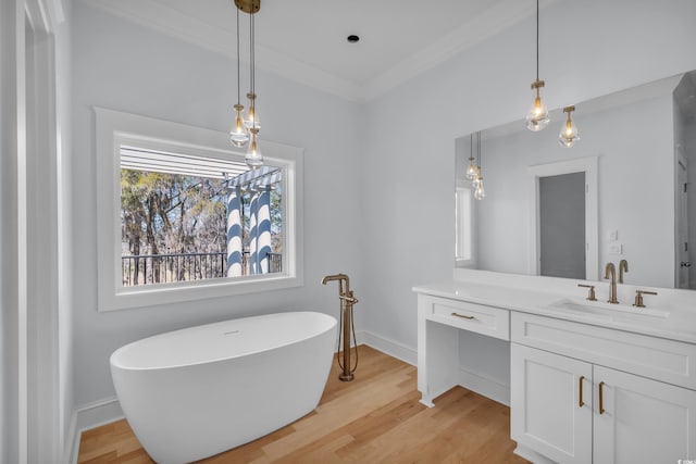 full bathroom with baseboards, ornamental molding, a soaking tub, vanity, and wood finished floors