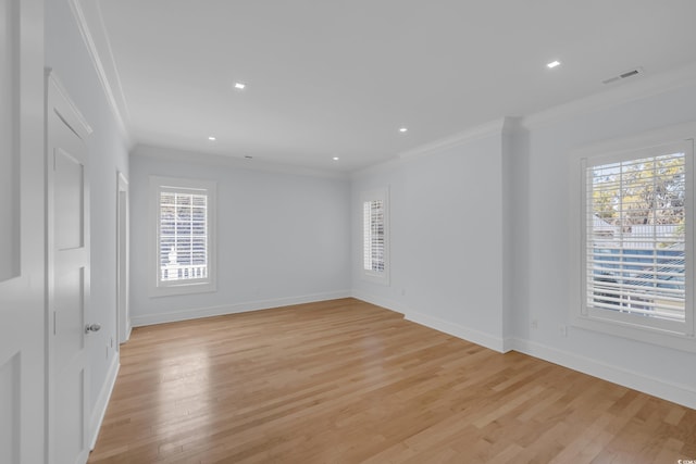 unfurnished room featuring crown molding, visible vents, light wood-type flooring, and plenty of natural light