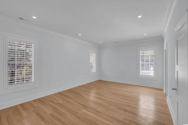 empty room featuring crown molding, a healthy amount of sunlight, light wood finished floors, and visible vents