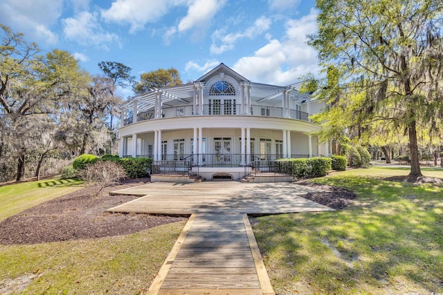rear view of house featuring a balcony, french doors, a lawn, and covered porch