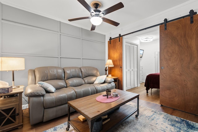 610 Putters Ln Unit H-109, Little River, SC 29566 - living room featuring wood finished floors, a barn door, ceiling fan, and a decorative wall
