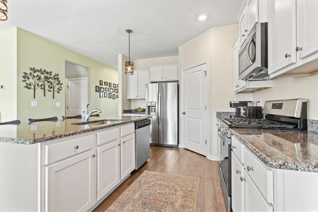 7037 Grant St, Little River, SC 29566 - kitchen with appliances with stainless steel finishes, a sink, white cabinetry, wood finished floors, and an island with sink