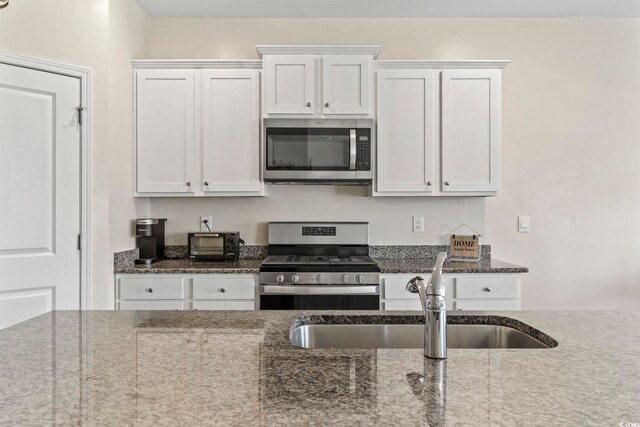 7037 Grant St, Little River, SC 29566 - kitchen featuring stainless steel appliances, a sink, white cabinets, and dark stone counters