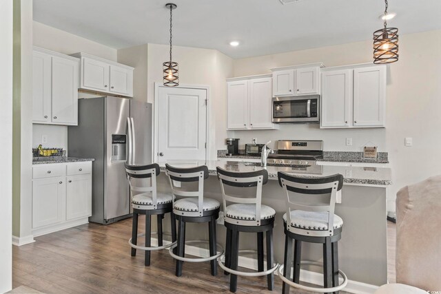 7037 Grant St, Little River, SC 29566 - kitchen featuring appliances with stainless steel finishes, white cabinets, a breakfast bar area, a center island with sink, and recessed lighting
