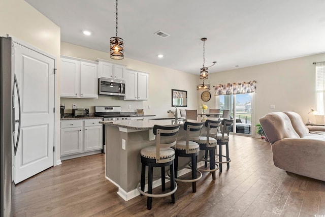 7037 Grant St, Little River, SC 29566 - kitchen featuring appliances with stainless steel finishes, open floor plan, hardwood / wood-style flooring, white cabinets, and a breakfast bar area