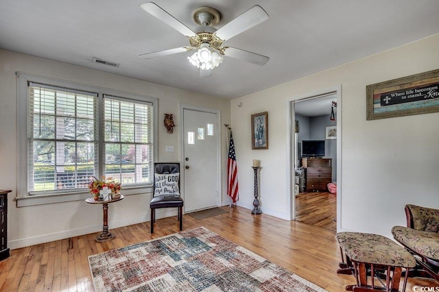 sitting room featuring light wood-type flooring, ceiling fan, baseboards, and visible vents